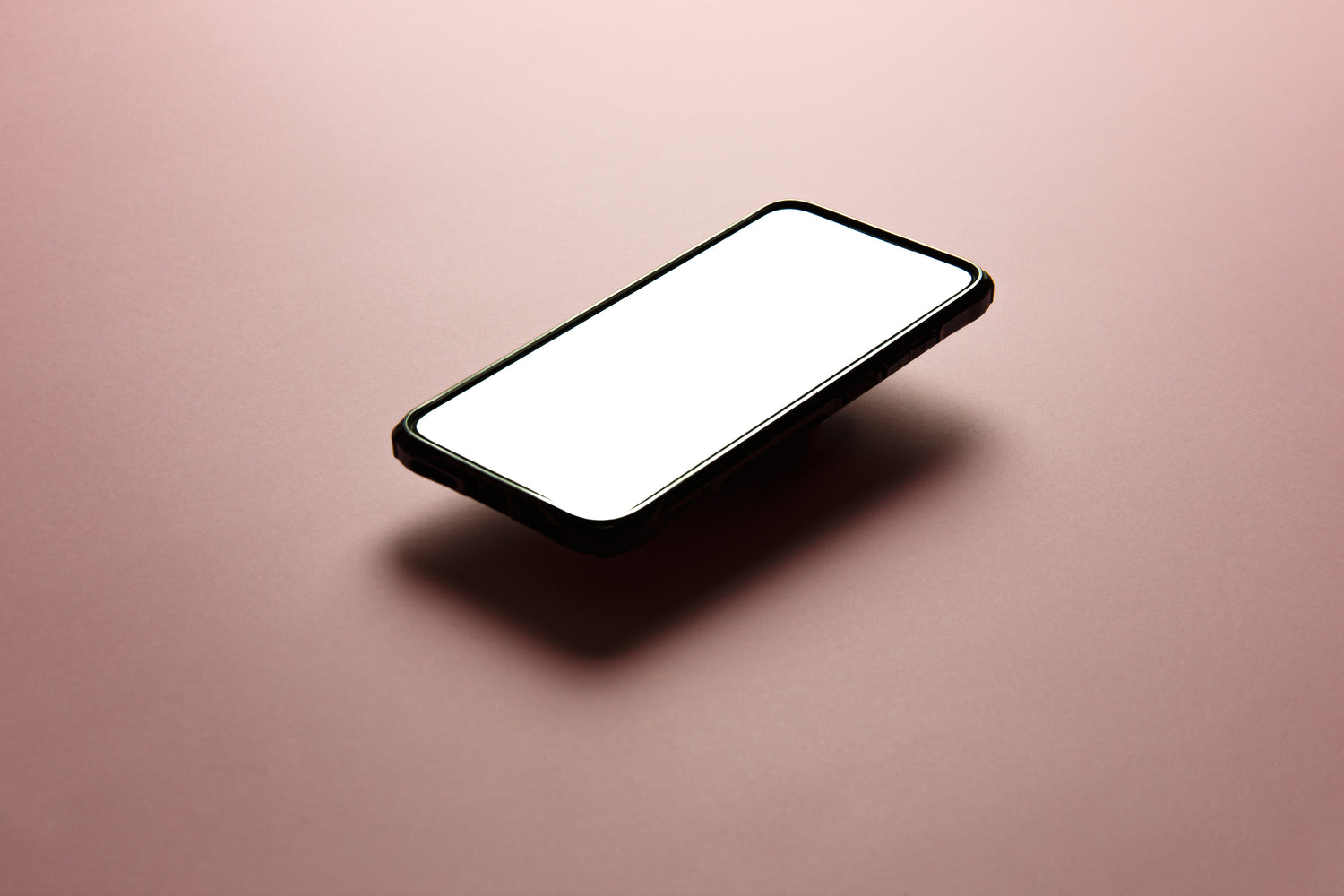 black iphone floating against a pink background